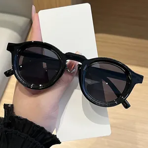 Retro round black sunglasses with UV protection held against white backdrop