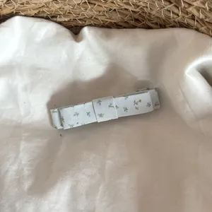 Détail d'une pince à cheveux nœud floral bleu clair sur un fond de lin blanc doux