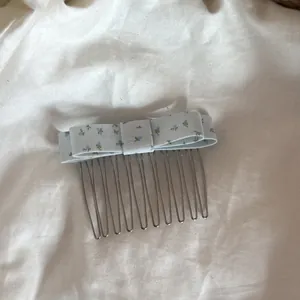 Vue détaillée d'un peigne à cheveux avec nœud à fleurs bleues sur un fond de tissu blanc