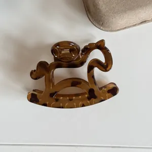 Detailed macro view of a tortoiseshell rocking horse shaped hair claw clip for women