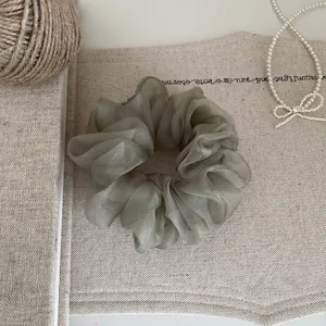 Elegantes olivgrünes Organza-Haargummi in der Detailansicht auf strukturiertem Leinen