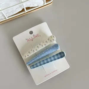 Detailed view of three blue themed hair clips featuring floral, dot, and plaid patterns