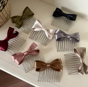 Detailed view of satin bow hair combs in eight elegant colors on a white surface