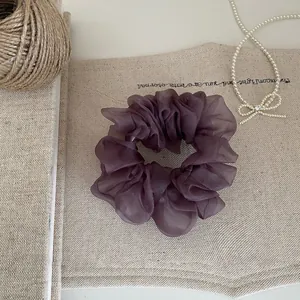 Nahaufnahme eines eleganten lila Organza-Haargummis auf rustikalem Segeltuch.