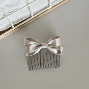 Close-up of elegant champagne satin bow hair comb with metallic teeth for styling