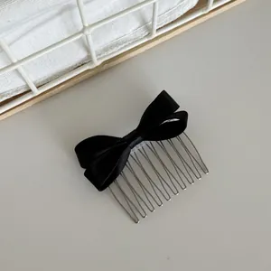 Detailed view of a elegant black satin bow hair comb for stylish side hair styling