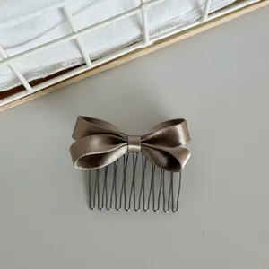 Close-up macro view of elegant champagne satin bow hair comb with metallic teeth detail
