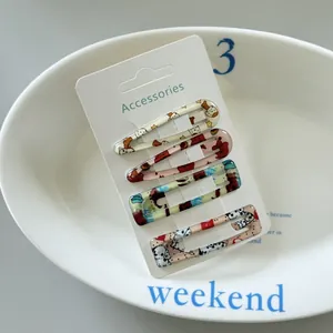 Detailed macro shot of four colorful patterned snap hair clips on a white display card