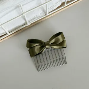 Close-up of elegant olive green satin bow hair comb with metal wire teeth detail.