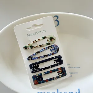 Detail view of 4-piece hair clip set with polka dot and grid patterns on a display card.