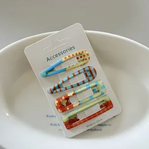 Close-up of 4 patterned hair clips with dots and checks on a white display card.
