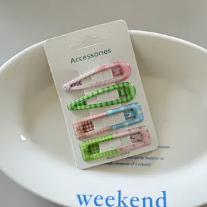 Close-up of four colorful polka dot and checkered hair clips on a display card.