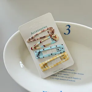 Detail view of four cute polka dot and checkered BB hair clips displayed on a white card.