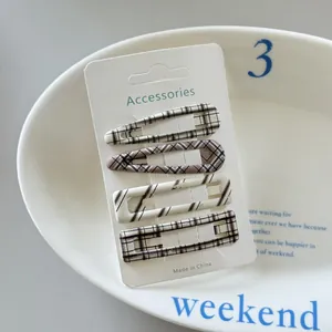 Detail view of four plaid pattern hair clips on a white display card.