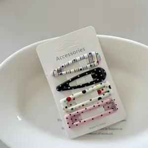 Detail view of four polka dot and striped hair clips on a white display card.