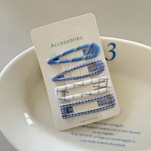 Detailed view of four blue plaid checkered hair clips on white accessories card