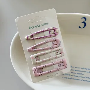 Detail view of 4-piece set plaid and striped hair clips on a white display card.