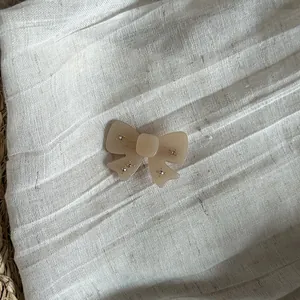 Detailed view of a sweet French style beige bowtie hair clip with sparkling rhinestones