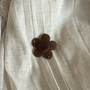 Macro view of French style translucent brown flower hair clip with heart detail on pleated fabric
