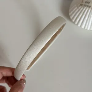 Detail eines minimalistischen cremefarbenen Satin-Haarreifs mit glatter Stoffstruktur