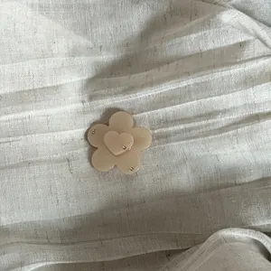 Close-up of a floral hair clip with heart detail and rhinestones on linen.