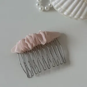 Detailed view of a sweet pink mesh scrunched fabric top on a silver metal hair comb