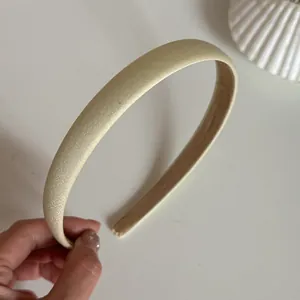 Detailansicht eines eleganten champagnerfarbenen Satin-Haarreifens mit Textur