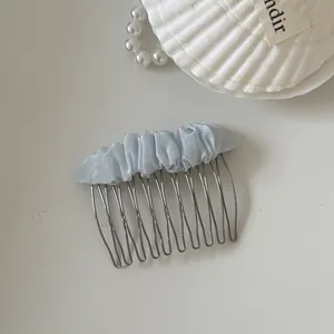 Detailed view of the light blue ruffled mesh fabric on a minimalist silver hair comb