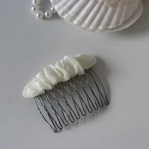 Detail of the elegant cream mesh fabric wrapped around a dark metal hair comb.