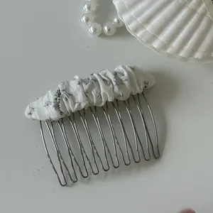 Macro view of a sweet floral pattern fabric gathered on a sturdy metal hair comb accessory
