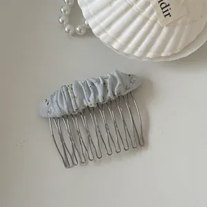 Close-up detail of a light blue floral mesh scrunchie hair comb on a white background.