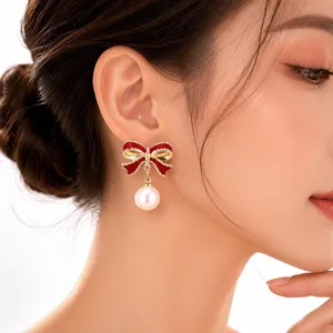 Primo piano di eleganti orecchini a fiocco rosso con una perla pendente su modella