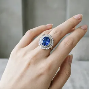 Vista ravvicinata di un anello halo di lusso con topazio blu ovale e diamanti su un dito