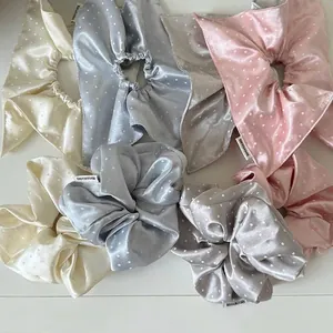 Detailed macro view of assorted satin polka dot scrunchie scarves in soft pastel tones and colors