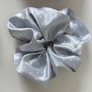 Close-up of a premium blue satin polka dot hair scrunchie showing soft fabric texture