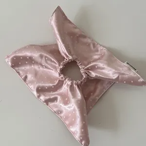 Close-up detail of a pink satin polka dot scrunchie showcasing its soft silk-like texture.