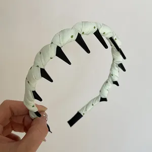 Close-up of polka dot fabric-wrapped headband with long black plastic teeth detail