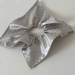 Close-up of a silver satin polka dot scrunchie with a unique square scarf design.