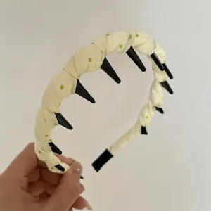 Detail view of yellow polka dot fabric wrapped headband featuring black long teeth grip