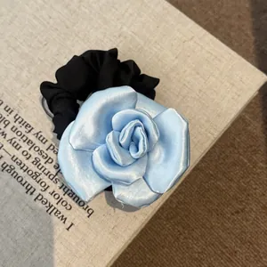 Elegant close-up shot of a light blue satin rose scrunchie placed on a vintage book