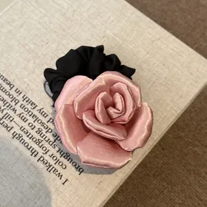 Detailed shot of a soft pink satin rose fabric hair scrunchie on a vintage book.