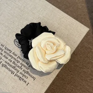 Close-up of the elegant cream satin rose detail on a black French style hair scrunchie