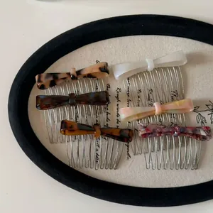 Close-up of elegant acetate bow hair combs in various marble patterns on a vintage display tray