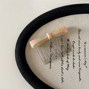 Detailed close-up of a pastel marble acetate bow hair comb with elegant metal tines