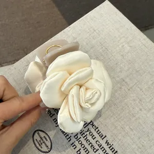 Detailed macro shot of a cream satin rose hair claw clip with elegant fabric textures