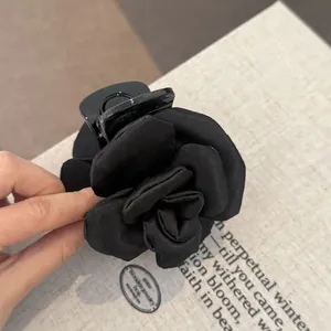 Detailed close-up view of an elegant black fabric rose hair claw clip with a soft satin finish