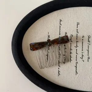 Close-up of elegant tortoiseshell acetate bow hair comb on vintage script fabric.
