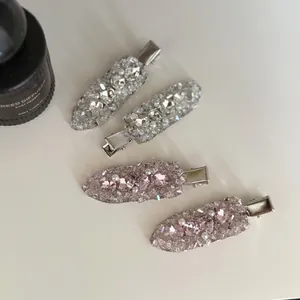 Detailed view of pink and silver crystal-encrusted duckbill hair clips on white background