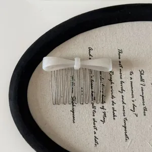 Detailed view of a white acetate bow hair comb with elegant metal tines for styling.