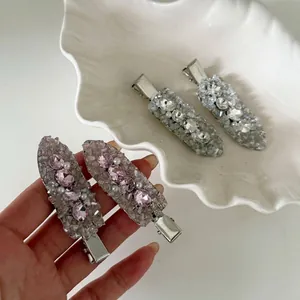 Elegant set of pink and clear rhinestone encrusted hair clips displayed on a shell dish